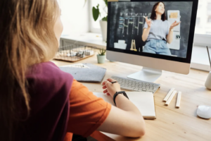 Menina sentada em frente ao computador, tento uma aula online. Inteligência artificial nos estudos.